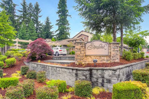 a stone retaining wall with a sign in front of a house